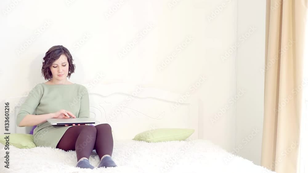 Young beautiful girl on bed looking information for a laptop. Young beautiful girl on bed looking information for a laptop.