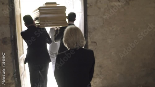Pallbearers leaving church with coffin followed by family photo