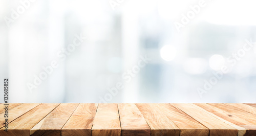 Wood table top on blur glass window wall building background.