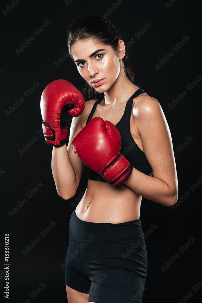 Woman wearing boxing gloves posing and looking at camera Woman wearing boxing gloves posing and looking at camera
