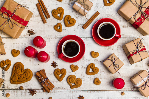 Two red coffee cups, gifts, cookies in the shape of a heart on a white wooden background © natapro