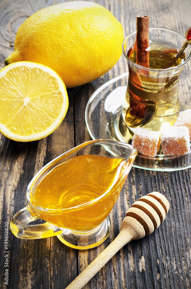 Honey, lemon and a cup of tea on a wooden table Honey, lemon and a cup of tea on a wooden table