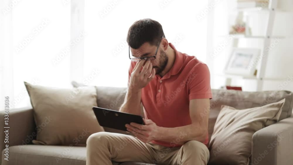 man with tablet pc tired from eyeglasses at home man with tablet pc tired from eyeglasses at home