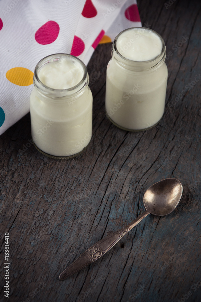 jars with white yogurt and spoon on the wooden background jars with white yogurt and spoon on the wooden background