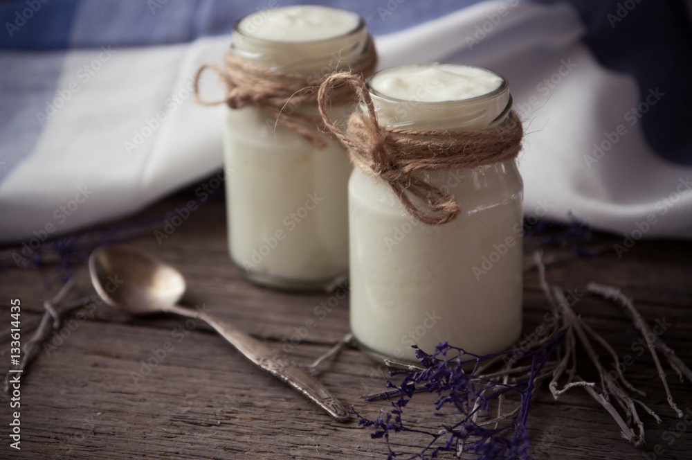 yogurt in jars on the wooden table with napkin, spoon and dried yogurt in jars on the wooden table with napkin, spoon and dried