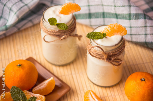 Fresh organig natural white yogurt in glass jars with tangerine photo