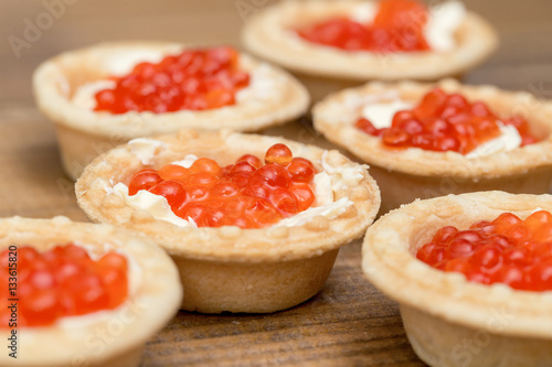 The Several tartlets with red caviar and butter on wooden brown table macro