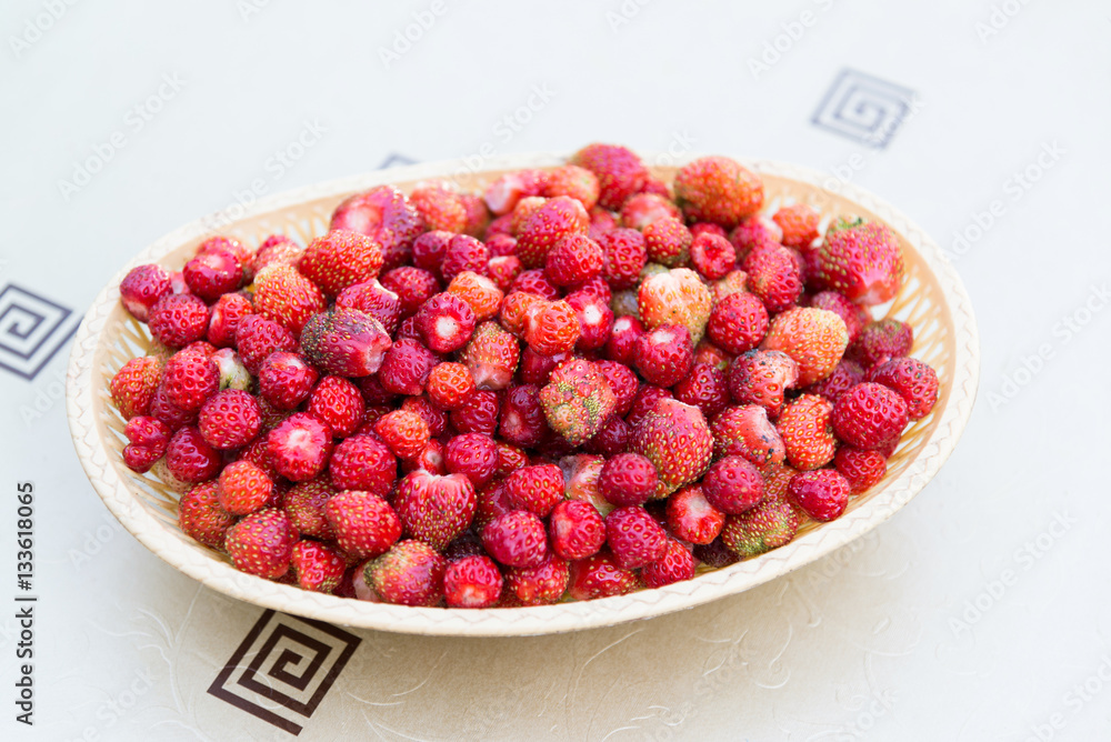 Ripe wild strawberry in wicker tray on a table Ripe wild strawberry in wicker tray on a table