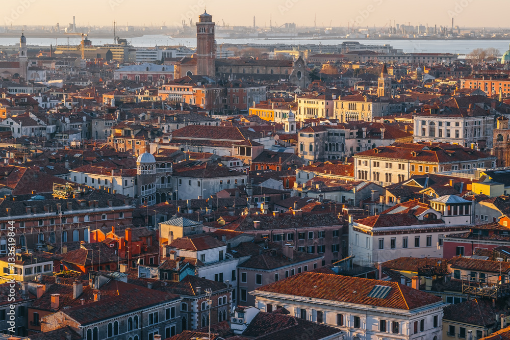 Aerial view of Venice, Italy, at sunset with rooftops of buildings and warm sunlight.