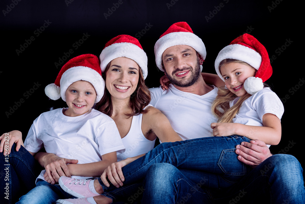 family in Santa hats looking at camera family in Santa hats looking at camera