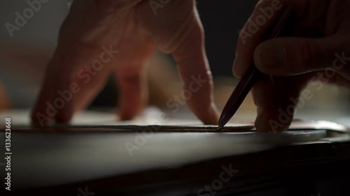 Closeup view of craftsman's hands working with a piece of leather on the table