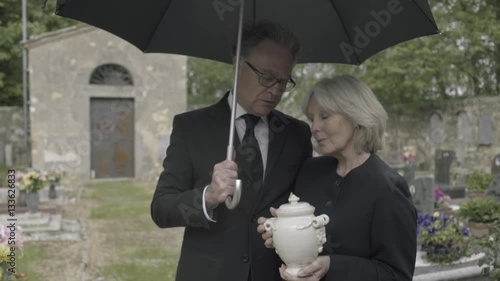 Mourners standing at funeral with cremation urn photo