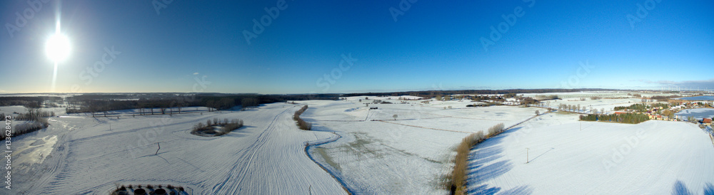 aerial view panorama of beautiful snowy landscape with sun and blue sky in germany aerial view panorama of beautiful snowy landscape with sun and blue sky in germany