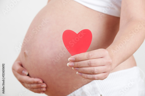 Close Up Of Pregnant Woman Holding Heart Shape