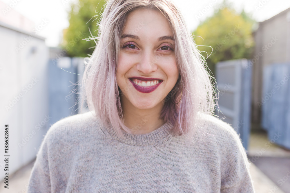 Portrait of young beautiful caucasian purple grey hair woman outdoor in the city looking at camera, smiling - happiness, carefree, serene concept Portrait of young beautiful caucasian purple grey hair woman outdoor in the city looking at camera, smiling - happiness, carefree, serene concept