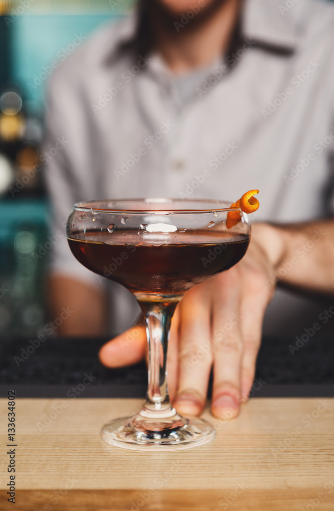 Young Barman offers alcohol cocktail in night club bar