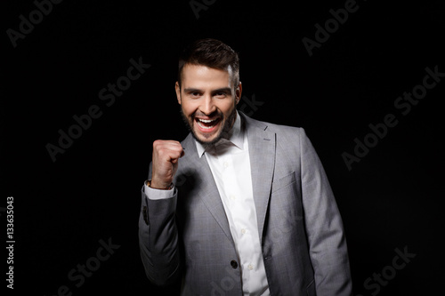 Young successful businessman rejoicing isolated on black background. Copy space.