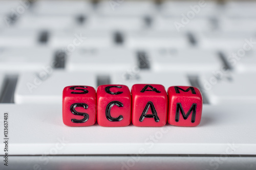 Scam word on the white keyboard showing swindles and fraud photo