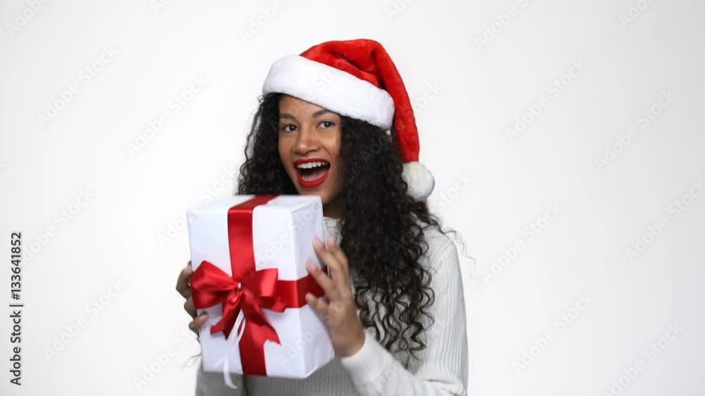 Happy African woman in white sweater and christmas hat catches the gift in studio Happy African woman in white sweater and christmas hat catches the gift in studio