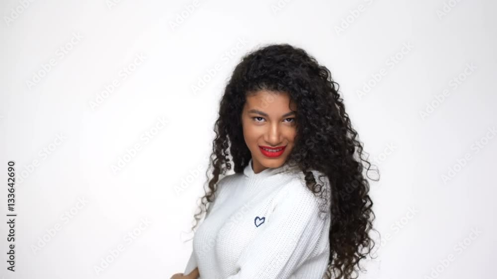 Young African woman in white sweater posing in studio and touching her hair Young African woman in white sweater posing in studio and touching her hair