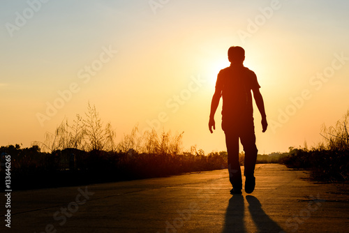 silhouette man walking on road at sunset background