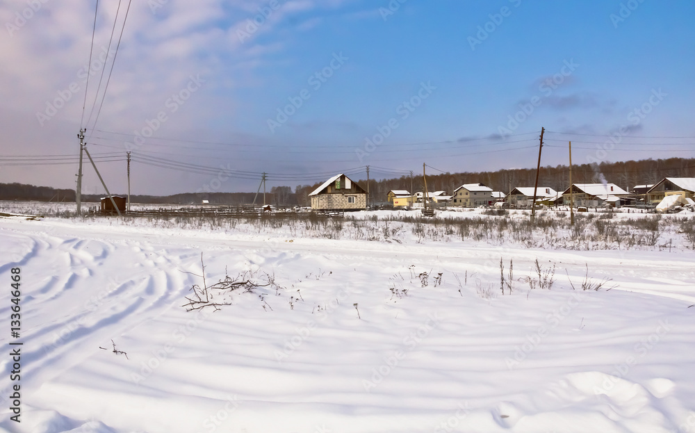 Winter rural landscape.Snowy road and houses on the edge of the village.