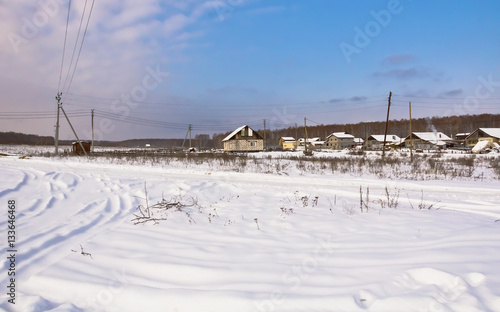 Winter rural landscape.Snowy road and houses on the edge of the village.