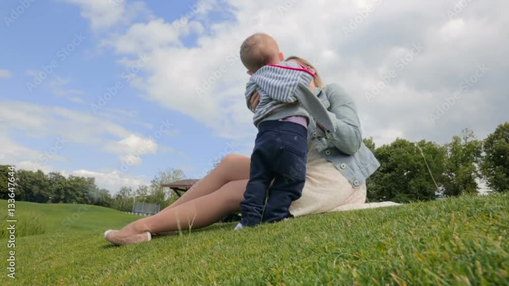 Cute 1 year old baby boy playing with mother on grass at park Cute 1 year old baby boy playing with mother on grass at park