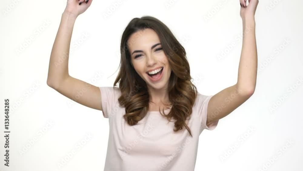 Happy brunette woman standing and dancing isolated on the white background Happy brunette woman standing and dancing isolated on the white background