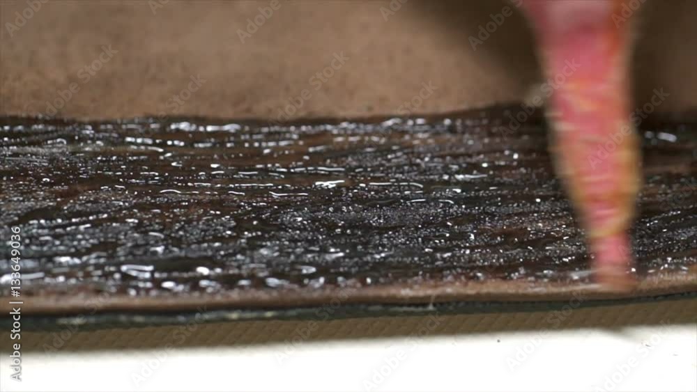 A craftsman applying the adhesive to the piece of leather in the workshop A craftsman applying the adhesive to the piece of leather in the workshop