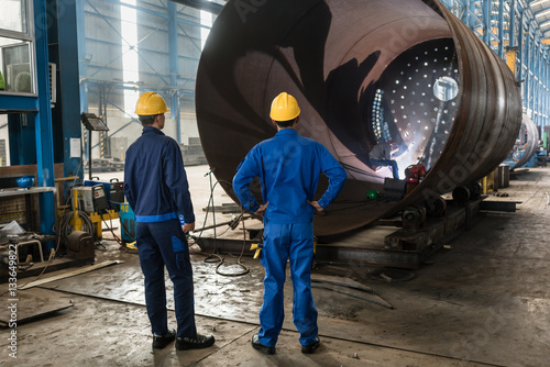 фотографія Workers supervising the manufacture of a metallic cylinder