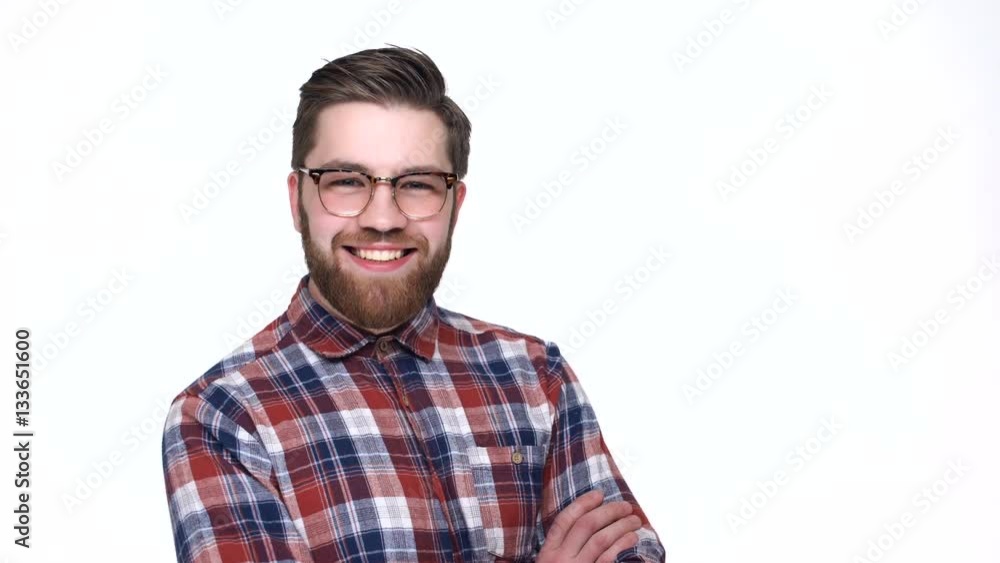Cheerful young bearded man in eyeglasses smiling at camera while standing isolated on white background Cheerful young bearded man in eyeglasses smiling at camera while standing isolated on white background