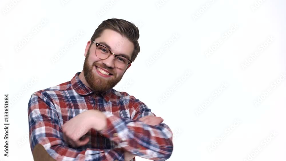 Confident young handsome man in shirt and eyeglasses pointing away and smiling while standing against white background Confident young handsome man in shirt and eyeglasses pointing away and smiling while standing against white background
