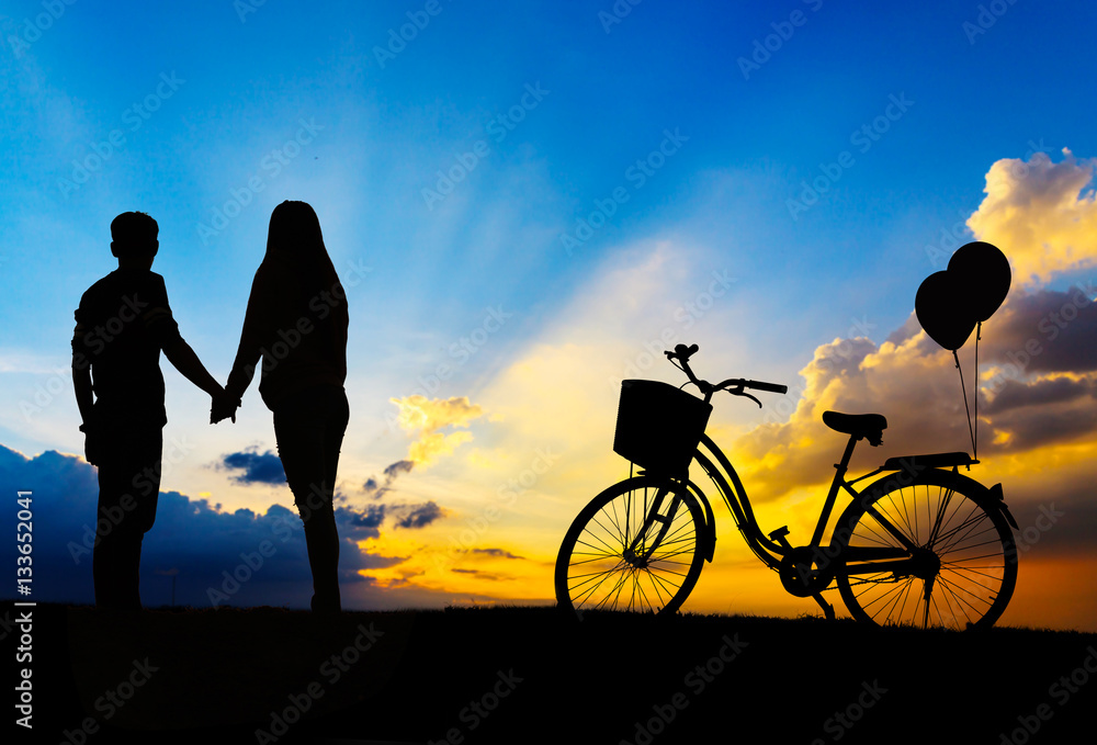 Silhouette of sweet couple in love happy time and bicycle in bea Silhouette of sweet couple in love happy time and bicycle in bea