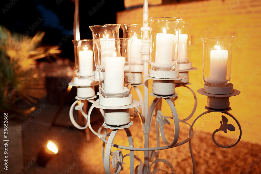 Large candleholder with white candles in glass vases stands outs Stock