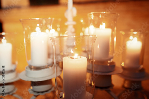 Large candleholder with white candles in glass vases stands outs