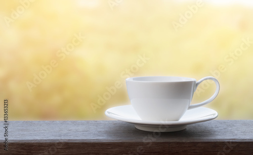 White coffee cup on wooden with sun light and blur background.