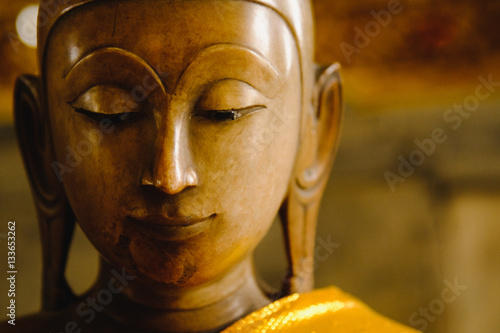 close up face on buddha head statue with Bokeh background and lighting effect.      Selective focus face buddha statue.