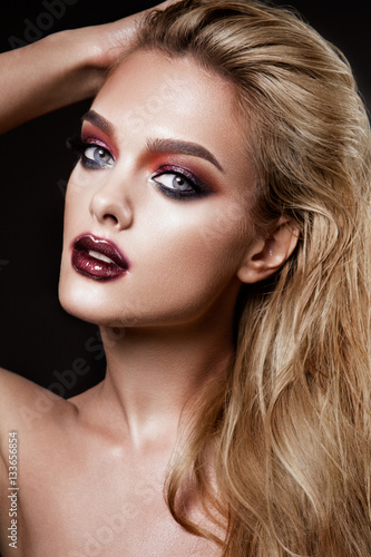 Portrait of beautiful young woman with long blonde hair and colored make-up