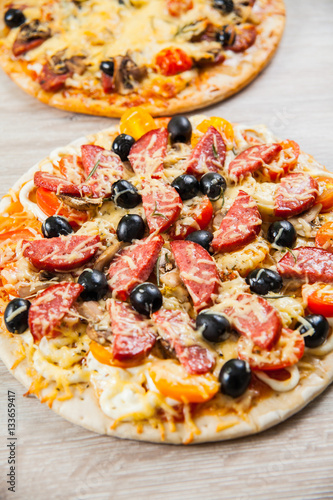 Top view two Pizza with mushrooms, olives and tomatoes, sausage. Rosemary and fresh vegetables. Freshly homemade