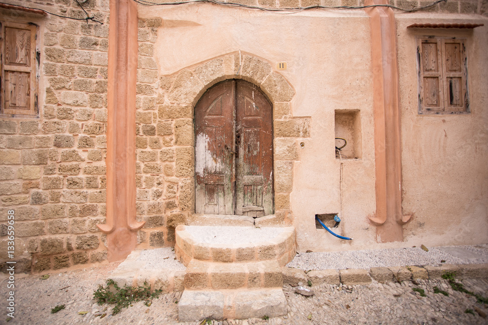 Old wooden door in the pink wall. Greece, Rhodes Old wooden door in the pink wall. Greece, Rhodes