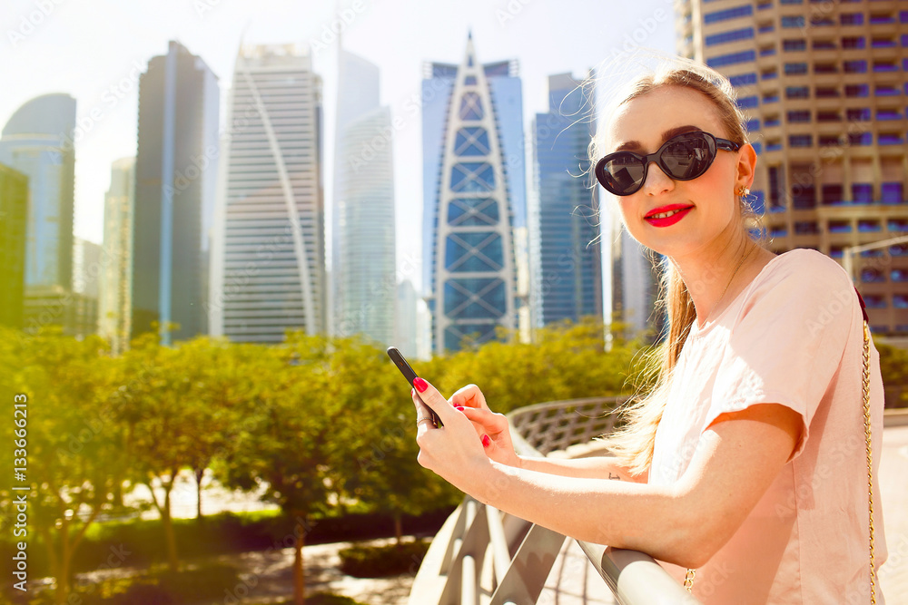 Smiling lady checks her iPhone standing on bridge before beautif Smiling lady checks her iPhone standing on bridge before beautif