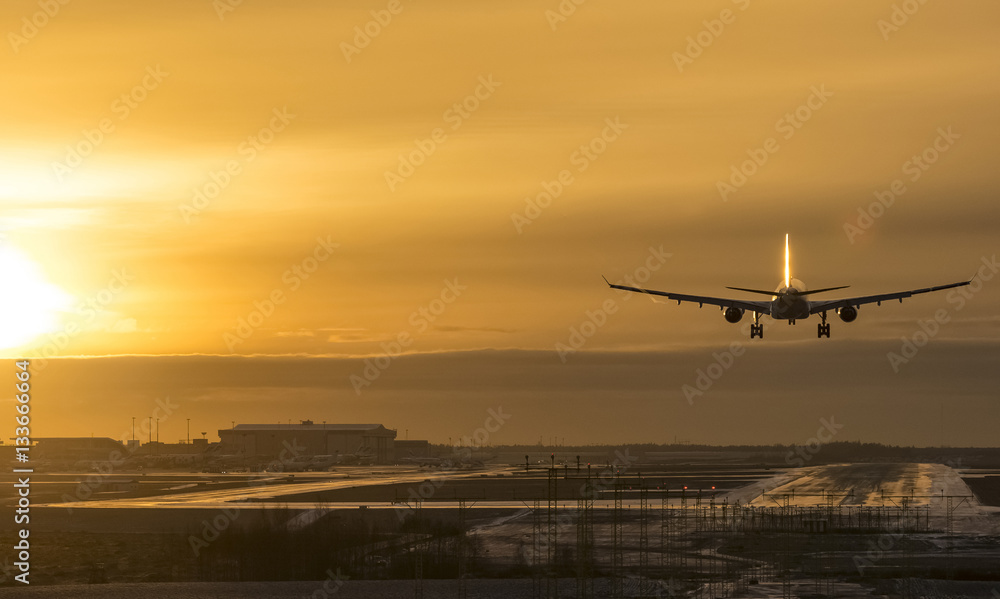 Commercial airliner landing to airport runway at sunset
