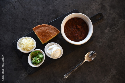 Chilli con carne, cornbread and accompaniments, overhead view