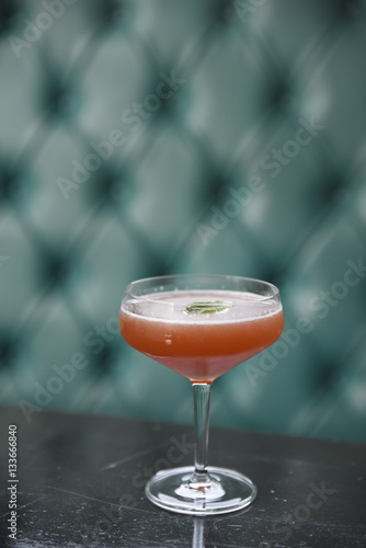 Drink in cocktail glass on table garnished with mint