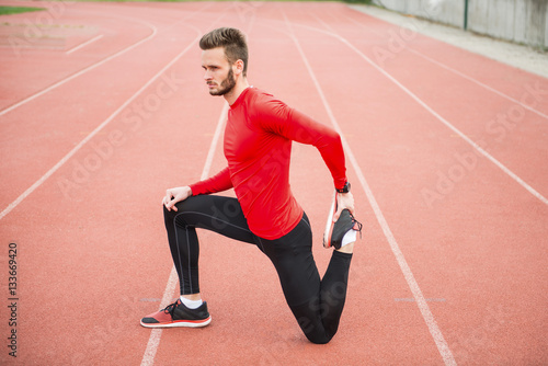 Doing some light stretching on a track. Athlete preparing for a run.