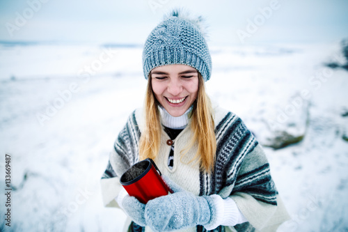 Breakfast in the mountains. Woman drinking warm tea in thewinter mountai. Young woman in a knitted shape is drinking tea