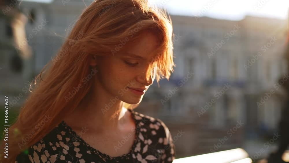 Young smiling cute redhead teen girl looking at her notepad ...