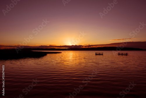 Germany  Kummerow  Atmospheric colorful sunset with lake  sunbeams  weirs  reed  horizon and sky.