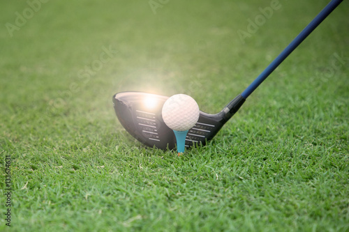 golf club and ball on a tee on a green grass